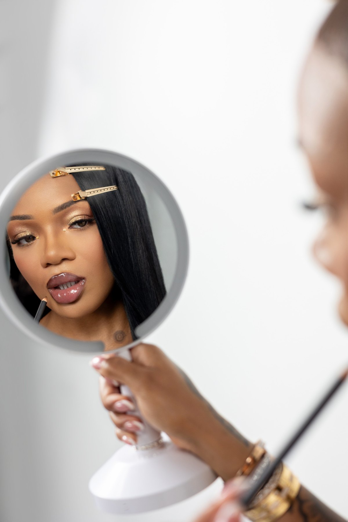 Gloria Woods applying lip liner in a hand mirror